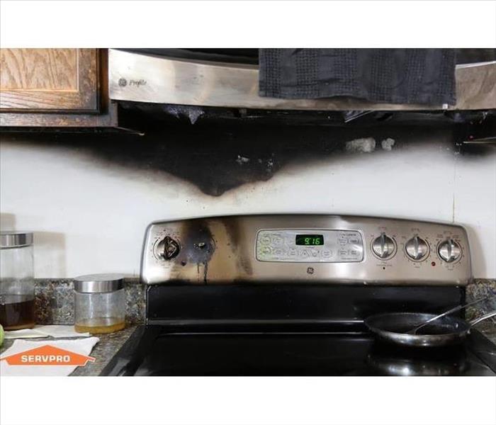 A kitchen stovetop and bottom of microwave burnt and affected by a kitchen cooking fire